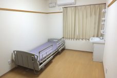 介護施設の個室。電動ベッドと窓、収納が配置された居室